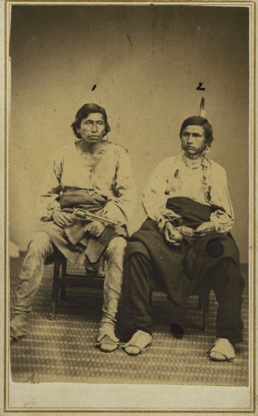 Seated portrait of Captain Whitewood (Mah-na-pay-honch-nee-kaw) and Mr. Tucker, both of the Ho-Chunk (Winnebago) tribe.  Whitewood was a member of the Bear Clan, a soldier chief, and was called "captain" by non-Indian people.