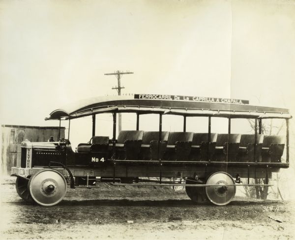 A side view of vehicle manufactured by the Winther Motor and Truck Company, used to carry employees to and from work in mines. This vehicle was apparently manufactured for export to Mexico, as the sign on top says "Ferrocarril De La Caprilla A Chapala".