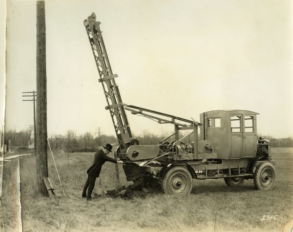 H.P. Lundskow demonstrating the usage of a posthole digger manufactured by the Winther Motors Inc., factory.