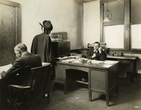 William Swift (Purchasing Agent) and Bill Evans (Assistant Purchasing Agent) at desks in the office of Winther Motor and Truck Company.