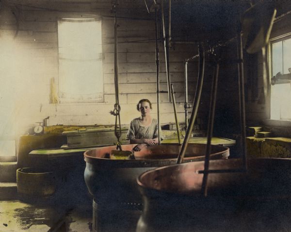 Hand-colored photograph of Frieda Jaggi at county line factory, the first family factory, which had a wood frame and heated kettles.  It was common for Frieda to work at the factory.