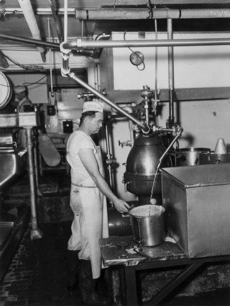 Kenneth Clark watches milk being separated, with cream going into the pail, at the Brodhead Cheese Factory.