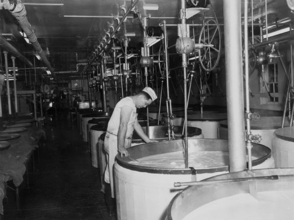 Interior view of the Brodhead Cheese Factory with Kenneth Clark working at the kettles.