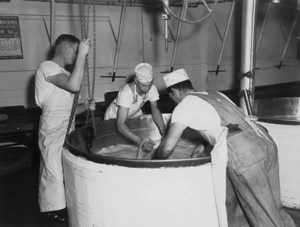 Men at the Brodhead Cheese Factory closing the cloth after dipping the cheese.