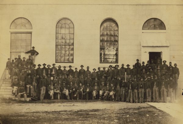 The 4th Maine artillery battery posed in front of a large building.