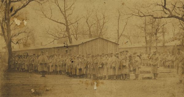 Large group of Union soldiers in formation by a barracks at Camp Douglas in Chicago, Illinois.