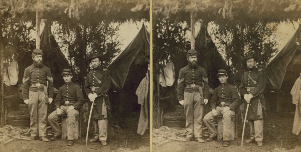 A stereograph of three Union soldiers in camp under a framework of branches.