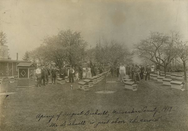 Apiary of August Diehnelt with a large group of people. Mr Diehnelt is just above the arrow.