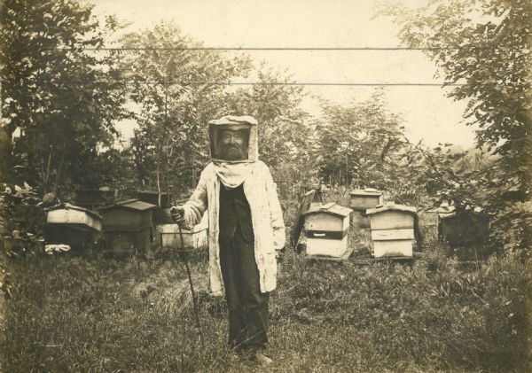George Hodges of Belmont, New York, in protective beekeeper clothing.  He was a warden and a beekeeper for a number of years.  His wife had died ten years prior to the taking of the photograph.  Mr. Hodges was originally from near London, England.