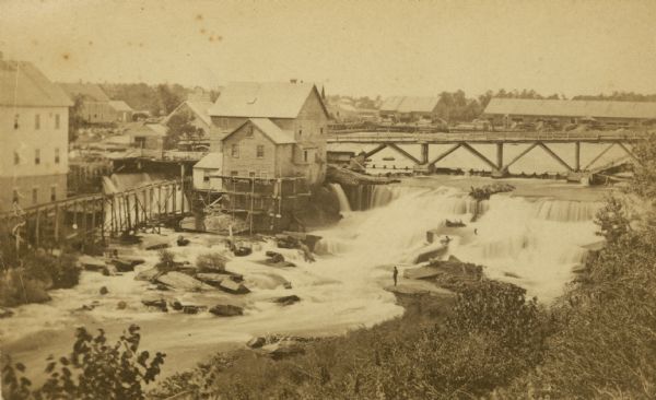 Elevated view of the Falls of Saint Anthony as viewed from the east, with a bridge spanning the falls, and a part of Saint Paul on the opposite shoreline.