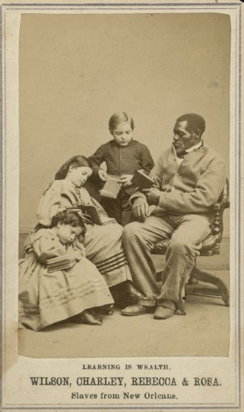 A carte-de-visite of a slave sitting with three children. The text at the bottom read: "Learning is Wealth. Wilson, Charley, Rebecca, & Rosa. Slaves from New Orleans."