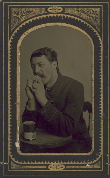 Tintype (ferrotype) of a man eating at a table.