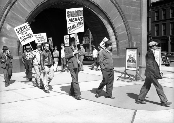 Public Workers Strike - Milwaukee members of the United Public Workers, tiring of a series of stalls on their legitimate wage demands, take to the street as pickets.  Those here are just a few of the men marching at the south side of City Hall, where even elevator service was discontinued.