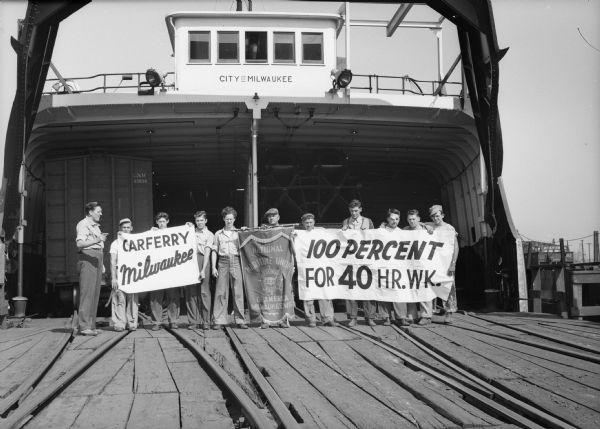 Crew of the railroad car ferry "City of Milwaukee" demonstrating for a 40-hour week and overtime pay.  The "City of Milwaukee" ferried Grand Trunk Western railroad cars across Lake Michigan.  The workers are members of the National Maritime Union of America.
