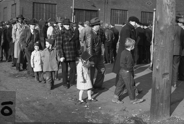 Members of Local 50, United Packinghouse Workers of America and their families walking the picket line.<p>"Picket Duty - Everyone's Job"  Even the youngsters, potential union members, co-operate to give strength to the picket line of Local 50, United Packinghouse Workers, on strike [against Plankinton Packing Company] since Tuesday, March 16."<br>- Wisconsin CIO News<p>Left to right: unknown man, Jake Gould, Jeffrey and Fred Erchul, Ludwig Fuerness and son, Carl Pielow walking with Jackie Erchul, and Wilfred Allison and son.</p>