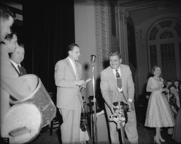 Presenting an outboard motor door prize at the annual dance of Local 7, Amalgamated Lithographers of America.<br>"Howie Roth presented the prizes with the help of his able assistant Frank Cieclak, Jr.  Man, that's a worthy smile for first prize, won by Lawrence Hettig and accepted by his son-in-law, pictured."</p>