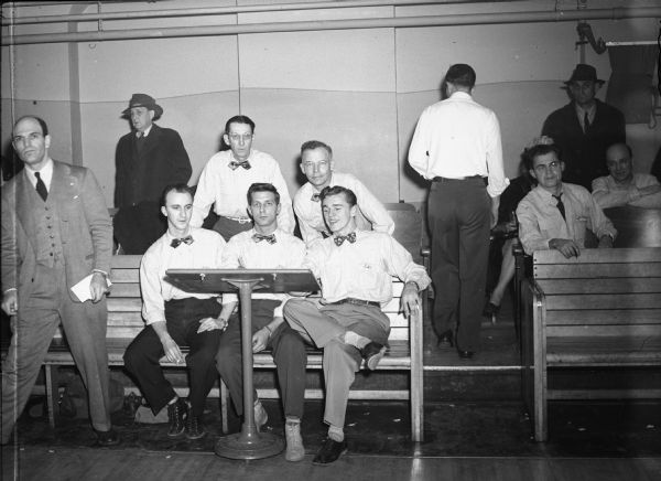 Already assured of the UAW Local 75 Bowling league title is the Cushions line-up shown here.  The sockers have lost only four games in 54 to date in the strike thumping done on the Antler's Alleys drives.  The club is hitting an 832 pace.
  - Wisconsin CIO News

Left to right, standing: Art Schuenke, averaging 178; and Ray Behrens (captain), 170.  Seated: Bill Doll, 149; Mike Nowak, 163; and Ed Wojciechowski, 172.
