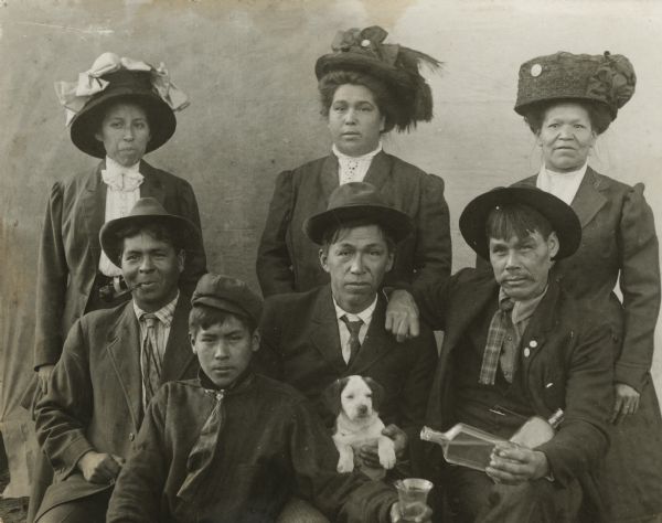 Group portrait of the Natwe Family with three women, three men, a boy, and a puppy.
