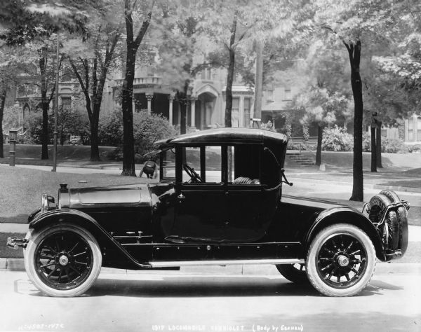 A 1917 Locomobile Cabriolet parked in a residential neighborhood.  Its body was produced by the W.S. Seaman Company.