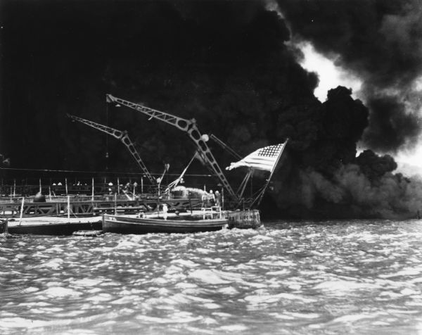 Sailors clear the stern of the battleship USS <i>West Virginia</i> in berth F-6 at Pearl Harbor, most likely after it was hit by at least a few of the 7 torpedoes and 2 bombs that pounded the ship.  The ship did not sink at Pearl Harbor but was saved through the work of its crew.