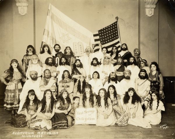 A group of Jewish people dressed as Old Testament characters standing in front of American and Israeli flags.