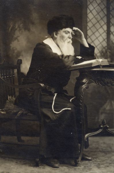 An unidentified man dressed as a chasid rabbi, sitting at a desk.
