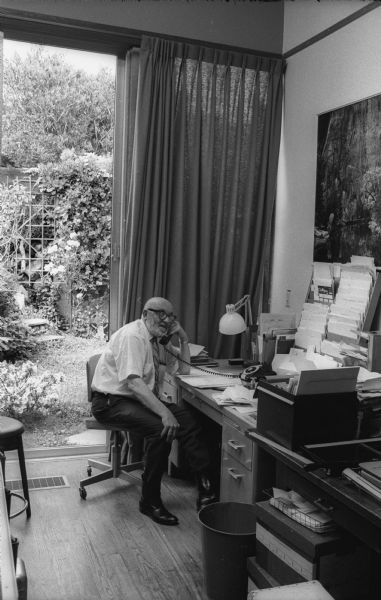 Photographer Ansel Adams talking on the telephone in his office at his home.