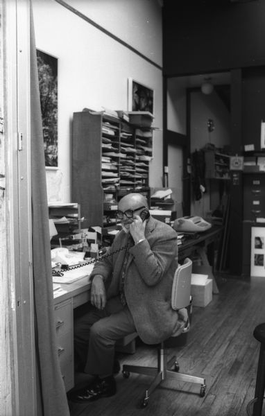 Ansel Adams, seated, talks on the telephone in his home office.