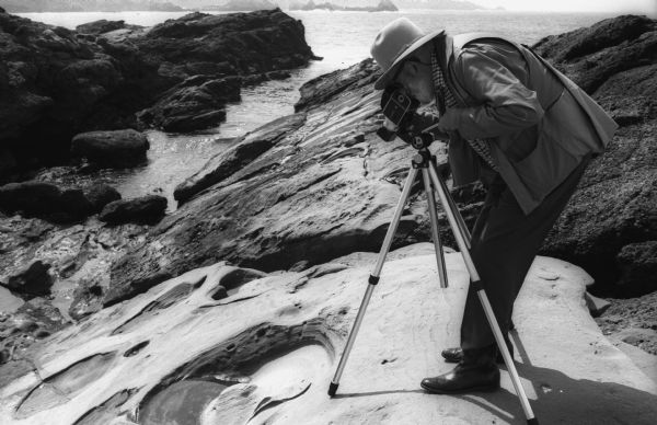 Ansel Adams makes a close-up photograph of a tide pool with his tripod mounted Hasselblad camera.