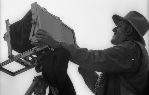 Low angle view of Ansel Adams loading a film holder into his field camera at Point Lobos.