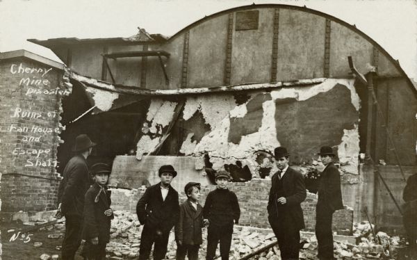 The ruins of the fan house and escape shaft after a mining disaster at Cherry mine. A group of men and children are standing in the foreground.