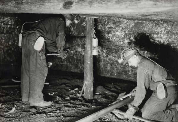 Two miners working in a tunnel or drift.