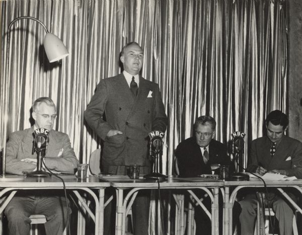 Philip Fox La Follette (second from right), during a broadcast of "Wake Up America" at the Lowell Thomas Radio Studio in Pawling, New York. The show broadcast from 2:00 to 3:00 P.M. There are NBC microphones on the table.
