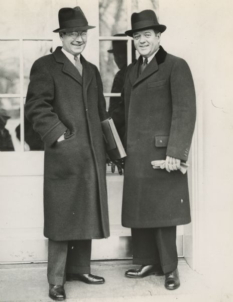 Philip and Robert La Follette, Jr., standing on a porch (the White House?), in long coats.