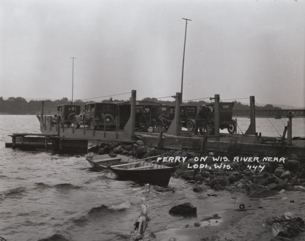 Car ferry on the Wisconsin River at Merrimac. A ferry has operated at this site since the 1840's. In 1924 the privately owned ferry was replaced by this wooden ferry which was operated by Columbia and Sauk counties, hence the name <i>Colsac I</i>. In 1933 the state began operating the ferry, the only free ferry in Wisconsin and a tourist attraction in its own right. Caption reads: "Ferry on Wis. River near Lodi, Wis."