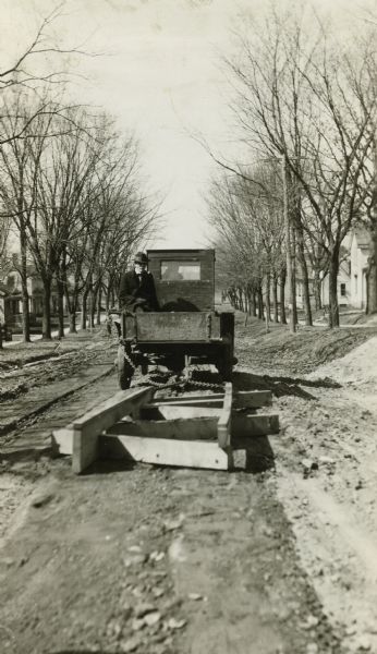 Road crew pulling a wooden, apparently homemade, road grader.  It is a variation on the "Wisconsin Road Planer," a design perfected by the Highway Commission from several types then in use.  Plans for the planer appeared in the 1926 Highway Maintenance manual.