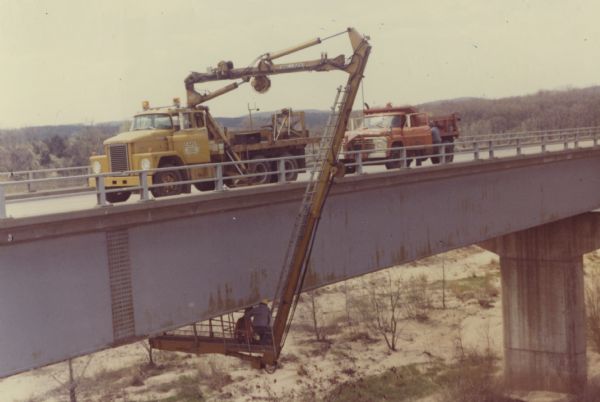 A crew from the Wisconsin Department of Transportation examines the condition of the underside of a concrete overpass.