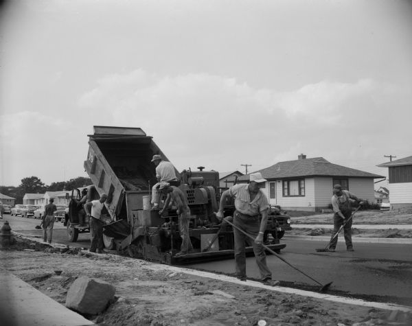 A construction crew blacktopping a Madison residential street.