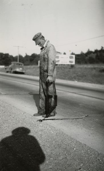 A patrolman, as local highway crewmen were known, filling a crack on State Highway 12 in Sauk County.