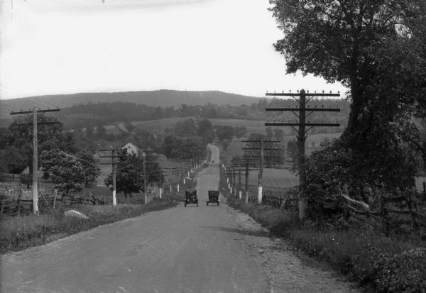 View down hill toward two cars passing each other along the Lincoln Highway near Bedford, Pennsylvania. The Lincoln Highway was conceived in 1912 by Carl Fisher, creator of the Indianapolis Speedway, as the nation's first improved, transcontinental highway. It ran from New York City to San Francisco. The route did not cross Wisconsin, but it did cross Illinois near the Illinois-Wisconsin border. Until 1925 many roads in addition to the Lincoln Highway were named. In that year the federal government adopted a national numbering convention in which all roads were numbered, with east-west roads numbered in multiples of 10 and north-south highway numbers ending in either 1 or 5. This portion of the Lincoln Highway became US 30.