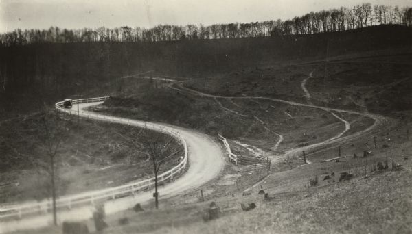 Loganville Road in Sauk County taken by the Wisconsin Good Roads Association.  The photograph was meant to create a contrast between the new improved road and its predecessor to the right and up the hill.