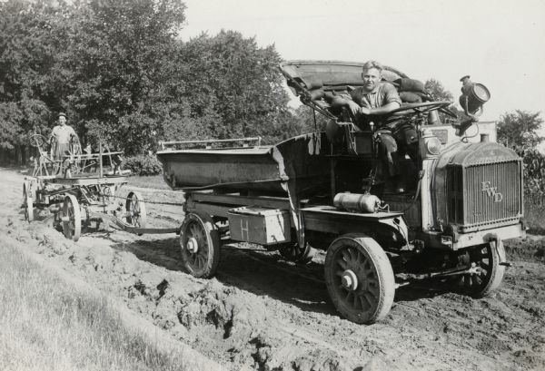 Cutting a Subgrade is the original caption of this photograph which shows a dump truck manufactured by the Four Wheel Drive Company of Clintonville pulling a road grader.