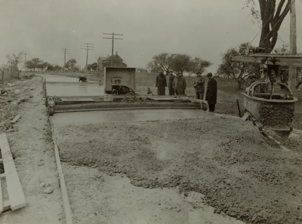 Workers and inspectors of a mechanized concrete pour somewhere in Milwaukee County. By 1920 Milwaukee was famous for its 18-foot wide concrete roads, the construction of which began in 1912.  By 1916 over 110 miles had been completed.