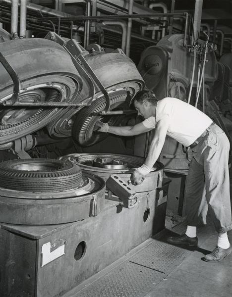 Employee of the United States Rubber Company at Eau Claire removing a tire from the curing mold.