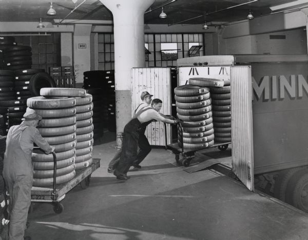 Employees at the United Rubber Company plant in Eau Claire load wrapped tires onto a truck for shipment.