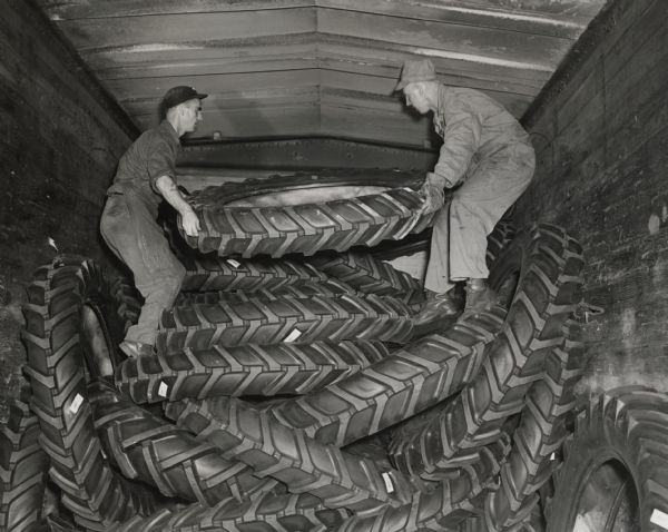 Two workers at the United Rubber Company plant at Eau Claire, Alfred Stokes and Eugene Stafford, loading large farm tires onto a railroad car for shipment.