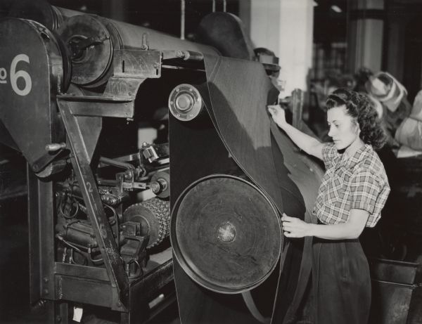 Isabel Olson, an employee of the United Rubber Company in Eau Claire, examining fabric for a pocket in a heavy service tire.  Although most women who joined the labor force during World War II ceased working at the end of the war, some did not.