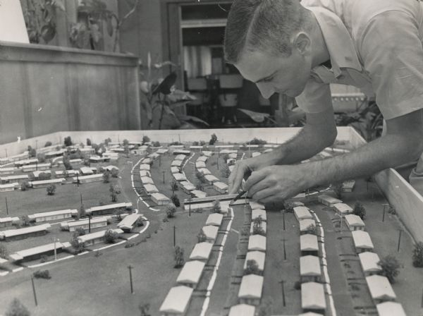 Propelled by good roads and lower property taxes, many Wisconsin towns became "commuter suburbs" to their larger neighbors during the 1950s and 1960s. While most suburban developments were initiated by real estate developers, the planner at work on a model here is Lt. E.J. Brannan, project engineer for the Capehart Project in Sun Prairie. The Capehart Project was designed to provide housing for Truax Field personnel.