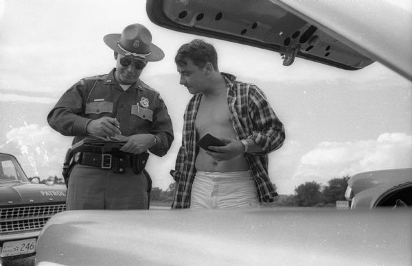 Highway patrolman issue's ticket ot motorist. Photograph taken by a <i>Milwaukee Journal</i> photographer who was covering the day of the Wisconsin State Highway Patrol officer on Highway 41.