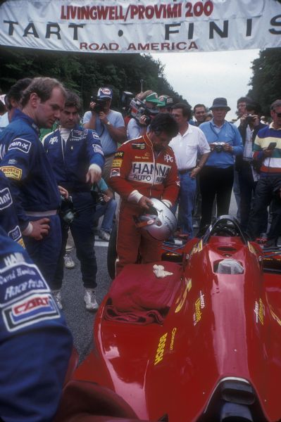 Mario Andretti, whom many consider to be the greatest race car driver of all time, at the start/finish line of the Road America race course at Elkhart Lake, Wisconsin.  Road racing is a long-standing tradition in Elkhart Lake where the first races were held on the village streets.  Andretti's win in 1987 was his third victory in the CART championship at Elkhart Lake.  In 2003 he was reponsible for the continuing relationship between the Champion Car World Series (CART) and Elkhart Lake.